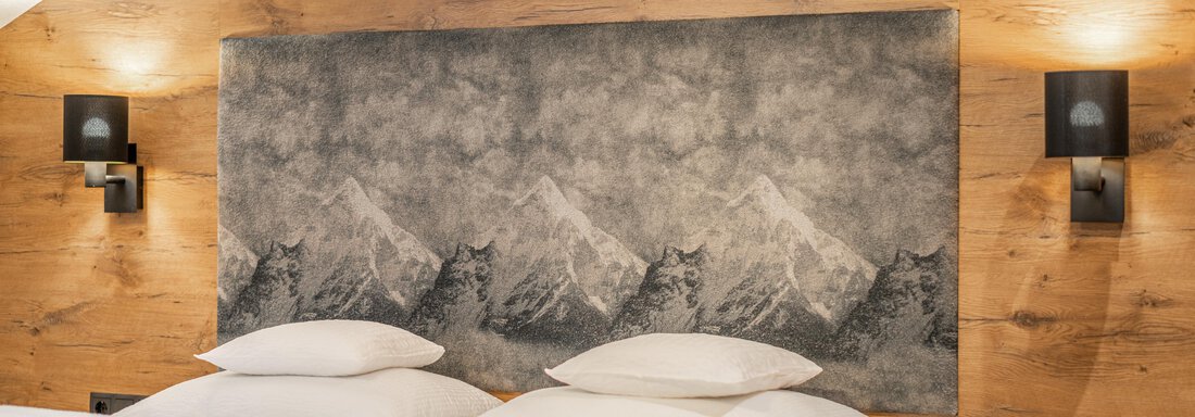 A modern bedroom with a double bed and a cozy wooden paneling. An artistic painting of mountains hangs on the wall. - Apart Hotel Garni Alt Kaisers - Sölden