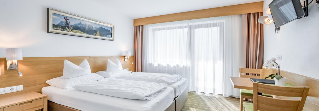 230620_090749 A modern bedroom with two single beds, wooden wardrobes, and a small table. Large windows provide plenty of daylight. - Apart Hotel Garni Wieser - Sölden