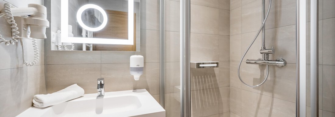 A modern bathroom with a shower cabin and a large mirror. The walls are bright and clean, and there are towels as well as a soap dispenser. - Apart Hotel Garni Wieser - Sölden