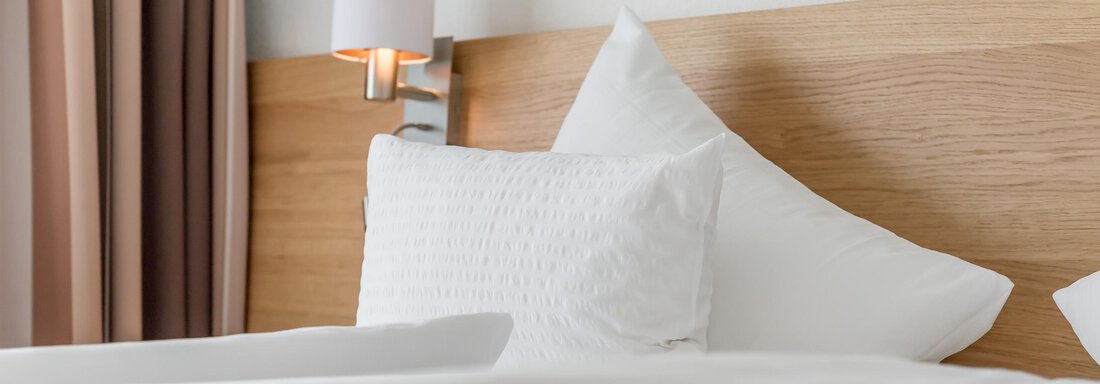 A modern bed with white pillows and a green bedspread. The walls are in soft colors and a lamp provides pleasant light. - Apart Hotel Garni Wieser - Sölden