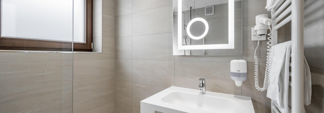A modern bathroom with a stylish sink and a lit mirror. The walls are painted in light, neutral colors. - Apart Hotel Garni Wieser - Sölden