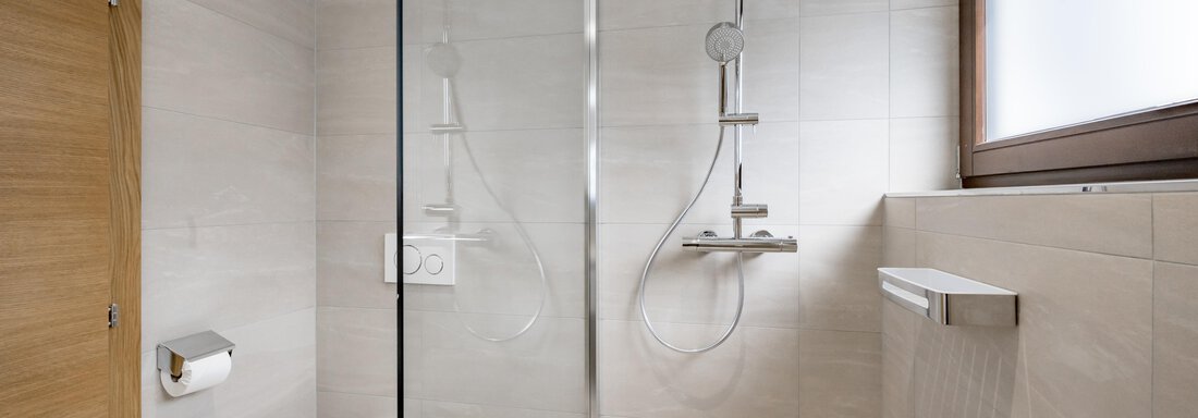 A modern bathroom with a glass shower and a toilet. The walls are in neutral tones, and there are large windows for natural light. - Apart Hotel Garni Wieser - Sölden