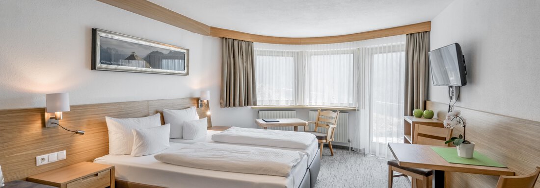 A modern hotel room with two single beds and a cozy seating area. Large windows provide plenty of daylight. - Apart Hotel Garni Wieser - Sölden