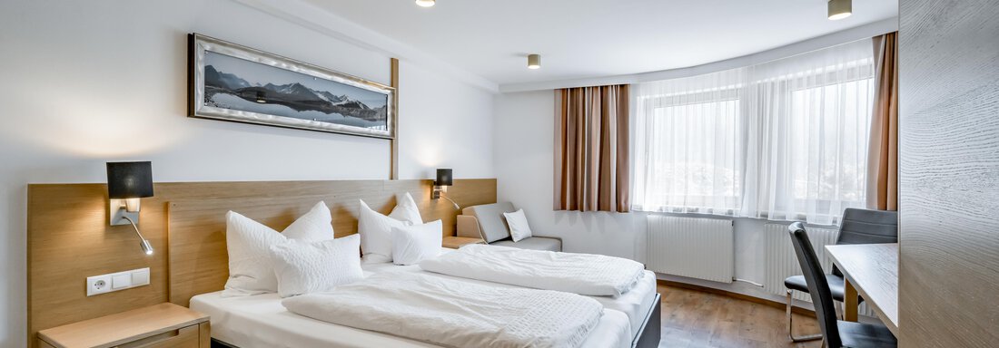 230620_111503 A modern hotel room with two single beds and wooden flooring. The room features large windows and a cozy seating area. - Apart Hotel Garni Wieser - Sölden