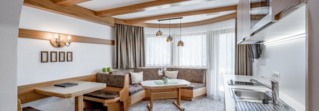 A modern and inviting living room with wooden details. The space features a seating area, a dining area, and an open kitchen. - Apart Hotel Garni Wieser - Sölden