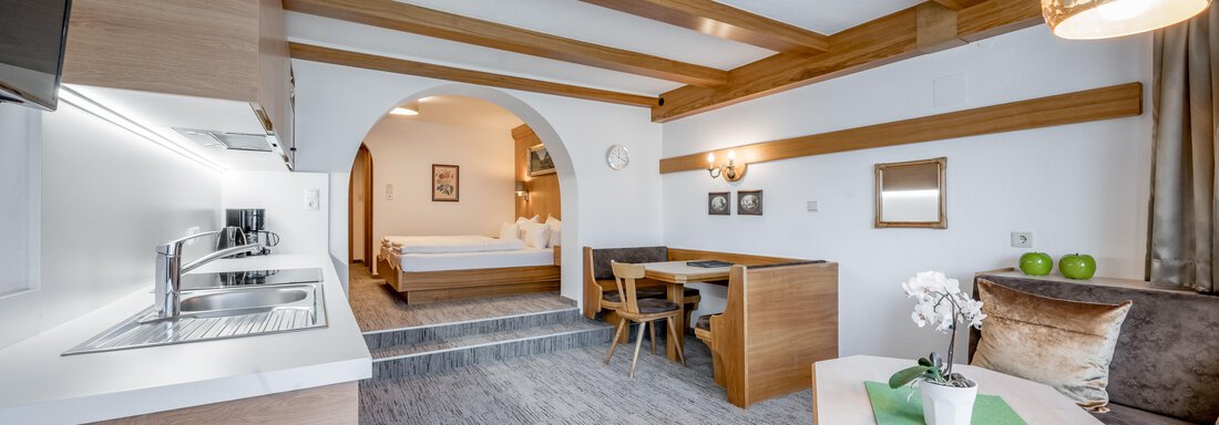 A modern apartment with wooden beams and a cozy living area. The kitchen is well-equipped, and there is a dining area with a table and chairs. - Apart Hotel Garni Wieser - Sölden