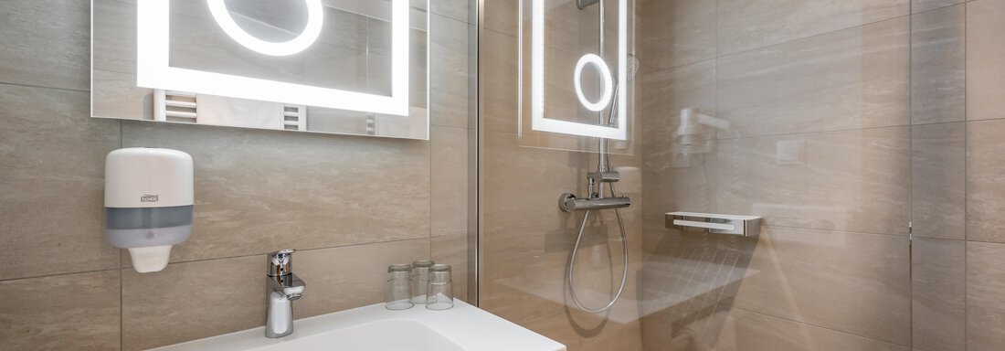 A modern bathroom with an elegant shower and a sink. The lighting in the mirror creates a pleasant ambiance. - Apart Hotel Garni Wieser - Sölden