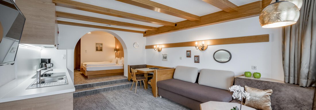 A cozy living space with open areas and wooden ceilings. The modern kitchen and the living room are tastefully furnished. - Apart Hotel Garni Wieser - Sölden