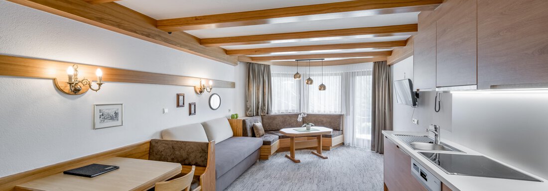 A modern apartment with wooden ceiling and bright interior. There is a seating area, a dining table, and a kitchenette. - Apart Hotel Garni Wieser - Sölden