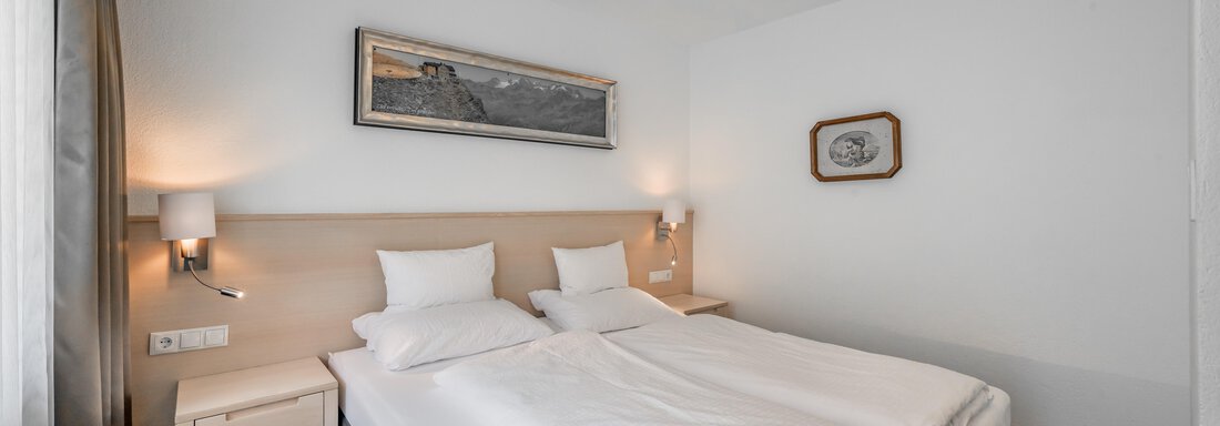 A modern bedroom with two single beds and neutral colors. The room has bright lighting and a minimalist design. - Apart Hotel Garni Wieser - Sölden