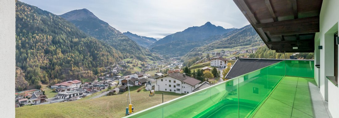 A modern terrace with green railing offers a view of the surrounding mountains and the valley. The landscape is brightly lit and appears inviting. - Apart Hotel Garni Wieser - Sölden