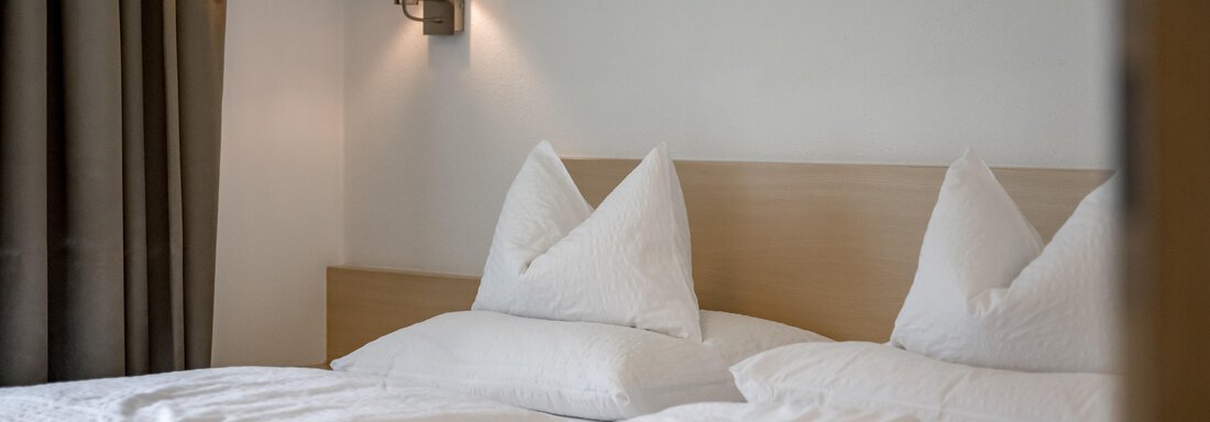 A cozy bedroom with two beds and white pillows. Gentle lighting creates a relaxed atmosphere. - Apart Hotel Garni Wieser - Sölden