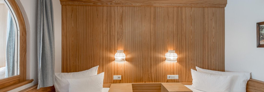 A cozy bedroom with two single beds and warm wooden walls. Soft lighting creates a pleasant atmosphere. - Apart Hotel Garni Wieser - Sölden