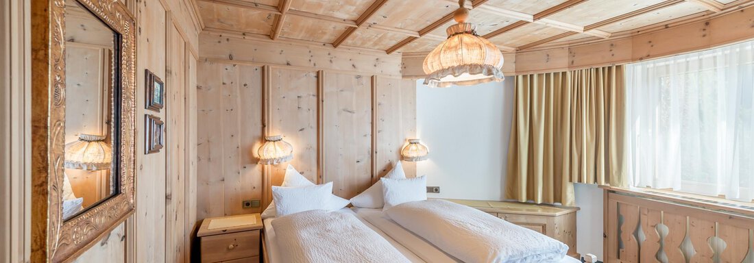 A cozy bedroom with wood paneling and a double bed. The warm light elements create an inviting atmosphere. - Apart Hotel Garni Wieser - Sölden