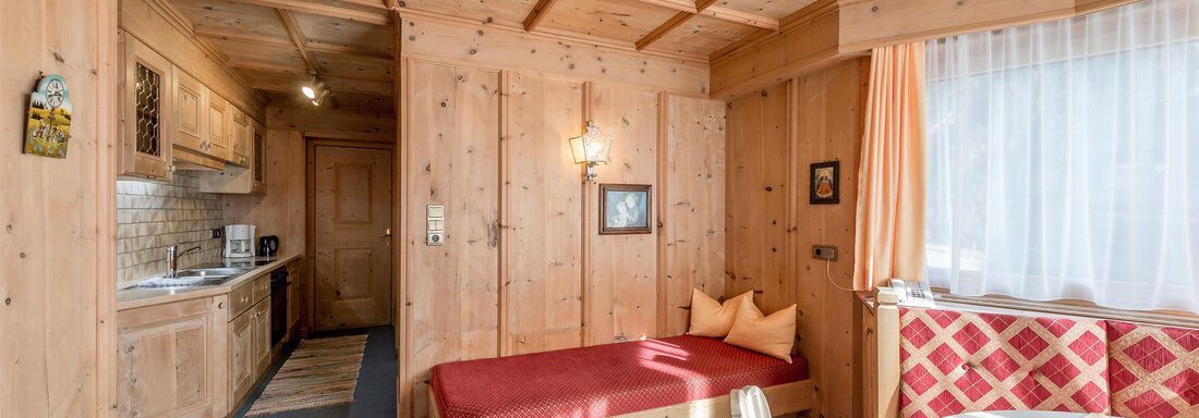 A cozy interior with wooden paneling and natural light. The apartment features a small kitchenette and a seating area. - Apart Hotel Garni Wieser - Sölden