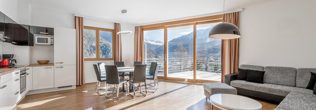 A modern, bright apartment with large windows and a view of the mountains. The space is equipped with a dining area, a kitchenette, and a cozy sofa. - Apart Hotel Garni Wieser - Sölden