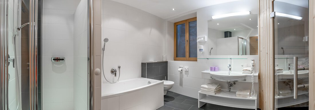 A modern bathroom with a shower and a bathtub. The walls are light and the space is well-equipped. - Apart Hotel Garni Wieser - Sölden