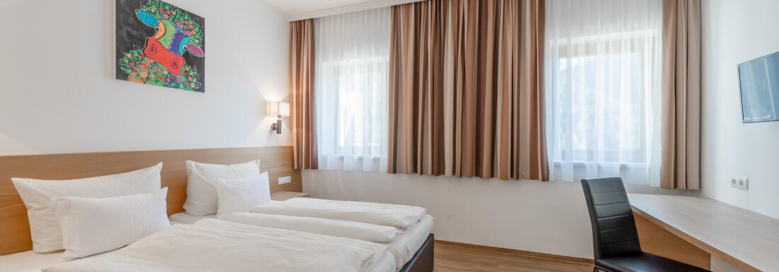A modern hotel room with two single beds and a desk. Large windows provide plenty of daylight. - Apart Hotel Garni Wieser - Sölden