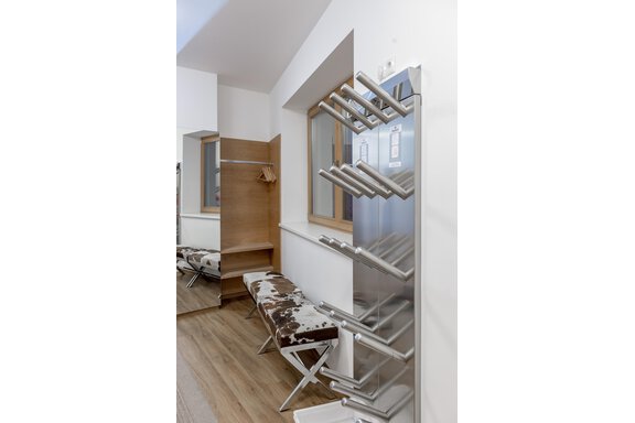 A modern changing room with a towel rack and a bench. The floor is made of wood and the atmosphere is bright and clean. - Apart Hotel Garni Wieser - Sölden