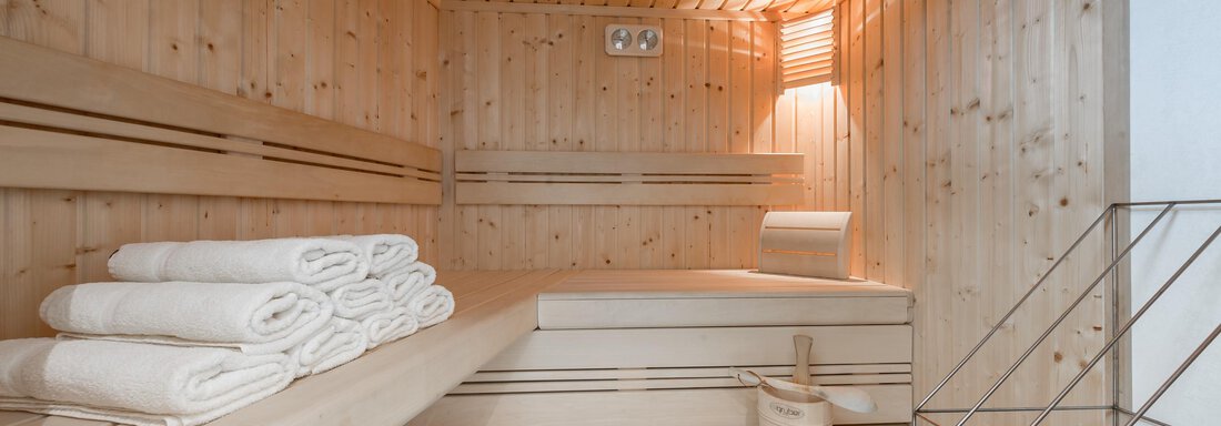 A cozy sauna with light wood interior. Clean towels are ready, and the lighting creates a relaxing atmosphere. - Apart Hotel Garni Wieser - Sölden