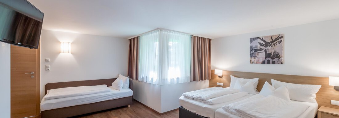 A bright, modern room with two beds and an additional sleeping space. Large windows create a pleasant light atmosphere. - Apart Hotel Garni Wieser - Sölden