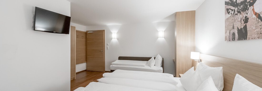 A modern room with two beds and a television. Bright colors and simple furniture create a pleasant atmosphere. - Apart Hotel Garni Wieser - Sölden