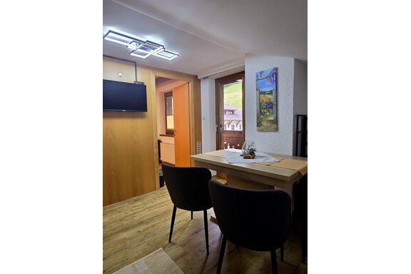A cozy dining area with a table and two chairs. A picture is hung on the wall, and a television is mounted on the wall. - Apart Tyrolis - Sölden