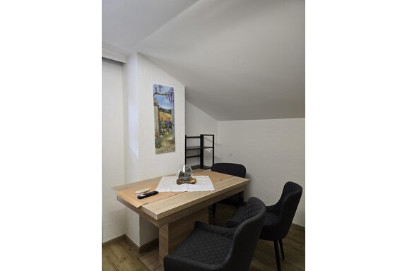 A small, cozy room with a wooden table and two chairs. A painting hangs on the wall and a shelf stands in the background. - Apart Tyrolis - Sölden