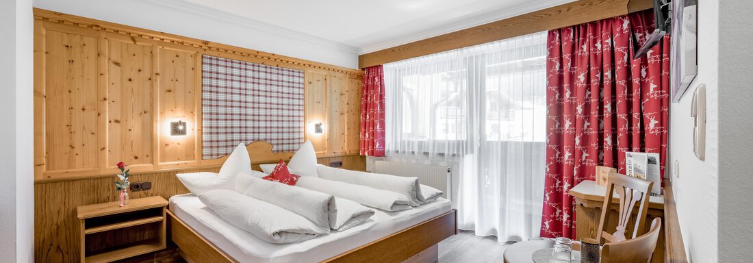 bedroom A modern bedroom with wooden walls and a large bed. The windows let in plenty of daylight, and the room is cozily furnished. - Apart Wiesengrund - Sölden