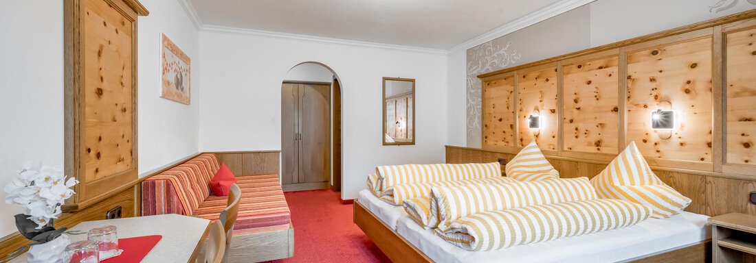 A cozy room with a large bed and striped pillows. The room is decorated in warm wood tones and offers an inviting atmosphere. - Apart Wiesengrund - Sölden