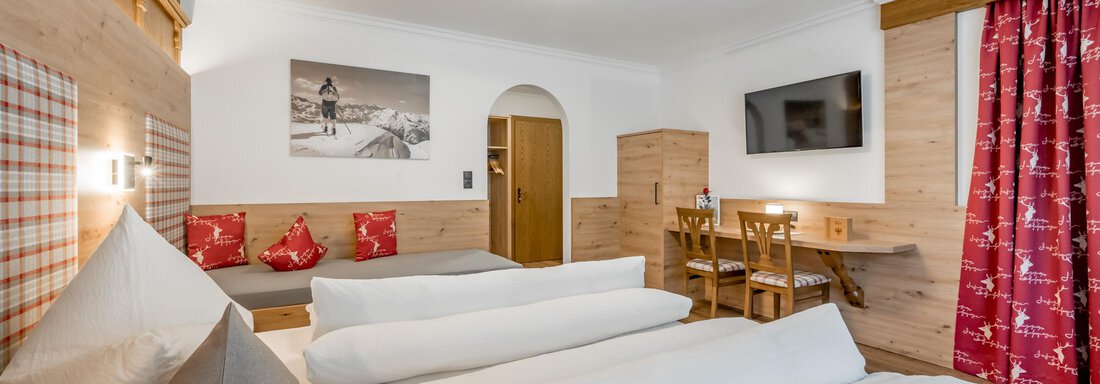 bedroom A cozy hotel room with wood decor, two beds, and pillows. The room is bright and features a television as well as a dining area. - Apart Wiesengrund - Sölden