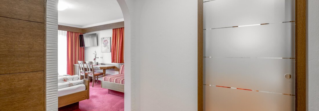 An inviting entrance area with a room in the background. The walls are light, the floor is red, and the room has a cozy atmosphere. - Apart Wiesengrund - Sölden