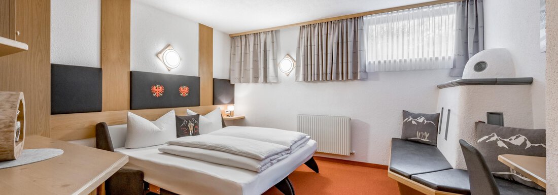 A cozy hotel room with a bedroom and a workspace. The decor is modern, and the walls are painted in warm tones. - Apart Wiesengrund - Sölden
