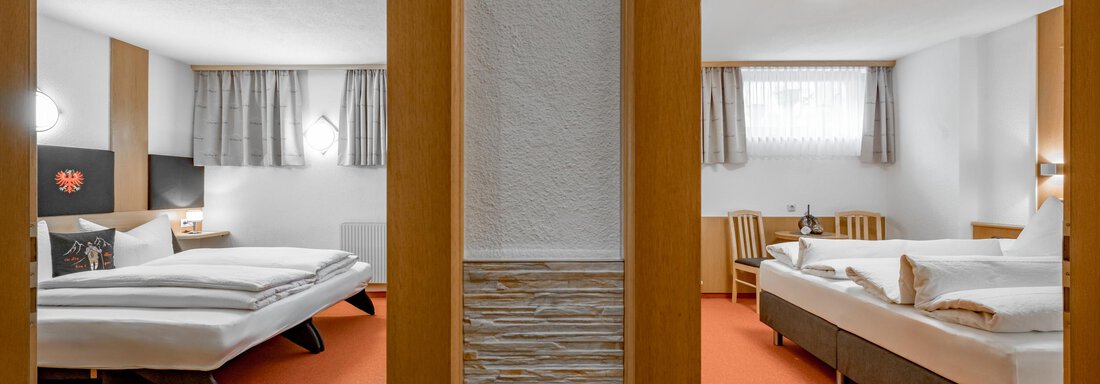 A modern hotel room with two beds and a cozy atmosphere. The floor is orange and large windows provide daylight. - Apart Wiesengrund - Sölden