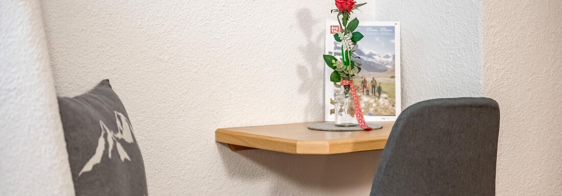 A small table with a flower and a picture. Next to a comfortable chair is a gray cushion. - Apart Wiesengrund - Sölden