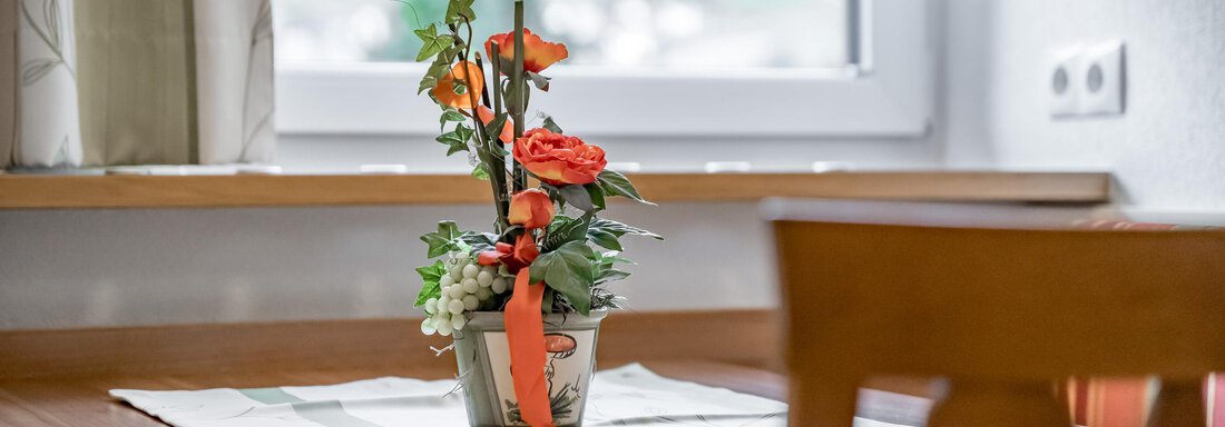 A beautiful table with a flower arrangement in a vase. In the background, there is a window with curtains. - Apart Wiesengrund - Sölden