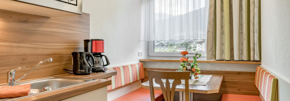 A cozy kitchenette with a small dining area. Bright colors and plenty of daylight create an inviting atmosphere. - Apart Wiesengrund - Sölden