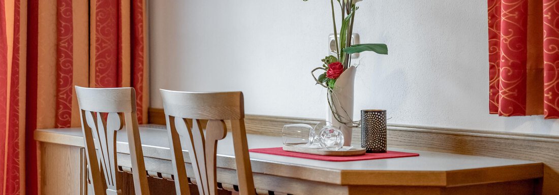 A cozy table with two chairs in a stylish room. On the table is a vase with fresh flowers and decorative elements. - Apart Wiesengrund - Sölden