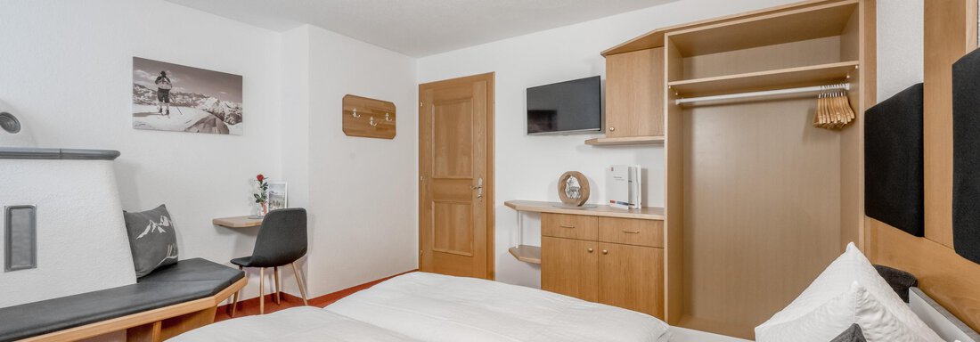 A modern room with two beds, a table, and chairs. The decor is bright and friendly, with a cozy atmosphere. - Apart Wiesengrund - Sölden