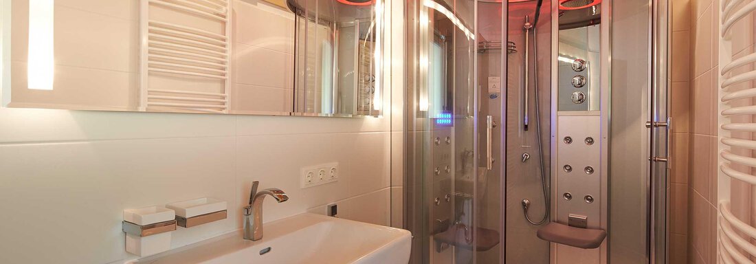 Ein modernes Badezimmer mit einer runden Duschkabine und einem eleganten Waschbecken. Die Wände sind hell und es gibt indirekte Beleuchtung. - Alpen Diamond Top 100 | 300 | 700 - Sölden