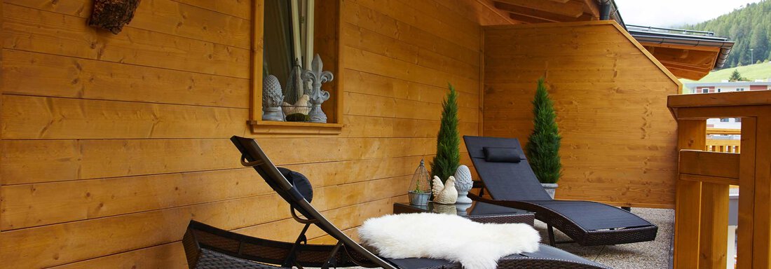 Ein gemütlicher Balkon mit zwei Liegen und einer weichen Decke. Die Wände sind aus Holz und es gibt kleine grüne Pflanzen. - Alpen Diamond Top 100 | 300 | 700 - Sölden