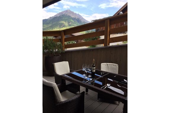 Ein eleganter Essbereich auf einer Terrasse mit Blick auf die Berge. Der Tisch ist gedeckt mit Weingläsern und einer Flasche Wein. - Alpen Diamond Top 100 | 300 | 700 - Sölden