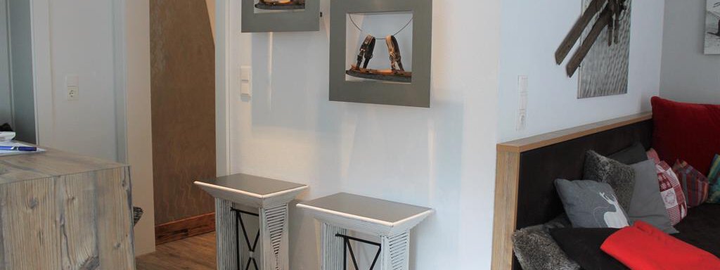 Ein moderner Innenraum mit zwei stilvollen Beistelltischen. An der Wand hängen gerahmte Bilder, und eine gemütliche Sitzecke lädt zum Entspannen ein. - Alpen Diamond Top 100 | 300 | 700 - Sölden
