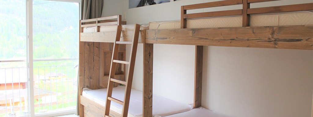 Ein helles Zimmer mit zwei Etagenbetten aus Holz. Große Fenster bieten einen schönen Blick auf die Natur. - Alpen Diamond Top 100 | 300 | 700 - Sölden