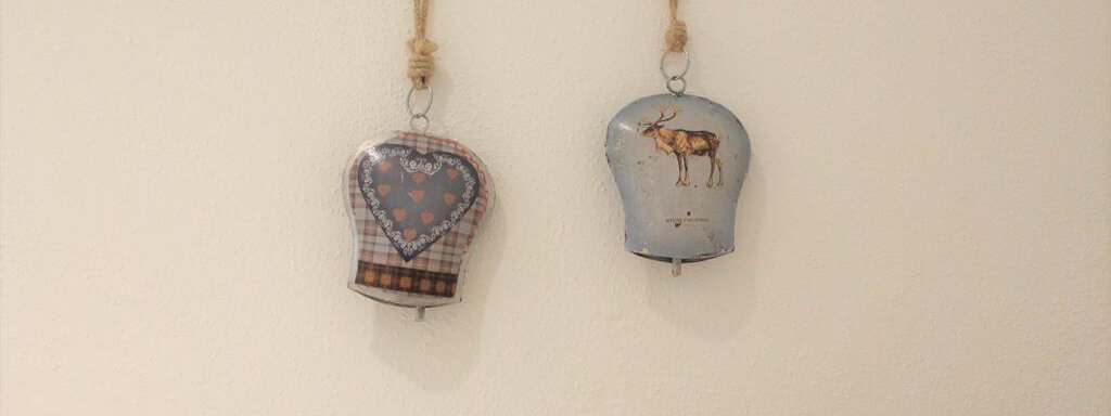 Zwei dekorative Aufhänger in Form von Kleidungsstücken hängen an einer Wand. Der linke Aufhänger hat ein Herzmuster, der rechte zeigt ein Reh. - Alpen Diamond Top 100 | 300 | 700 - Sölden