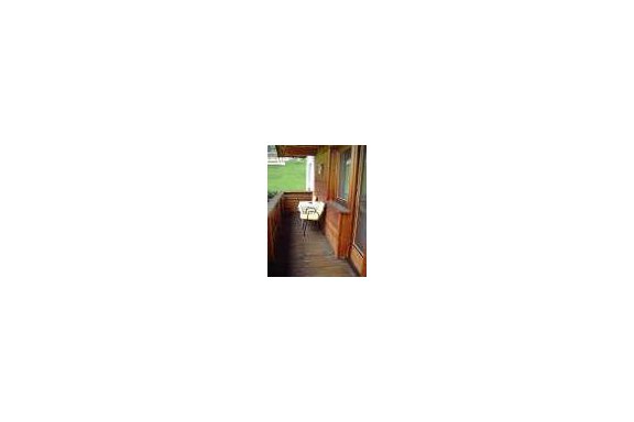 A narrow balcony with wooden walls and a small table. The surroundings are green and inviting. - Appartement Almhof - Sölden