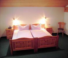Zimmer A cozy bedroom with a wooden double bed and two nightstands. The lighting creates a pleasant atmosphere. - Appartement Almhof - Sölden