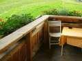 A cozy outdoor area with a table and a chair. In the background, green plants can be seen. - Appartement Almhof - Sölden