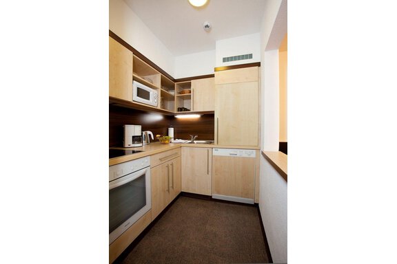 A modern kitchen with light wood cabinets and modern appliances. The countertop is well organized and clean. - Appartement Alpin - Sölden