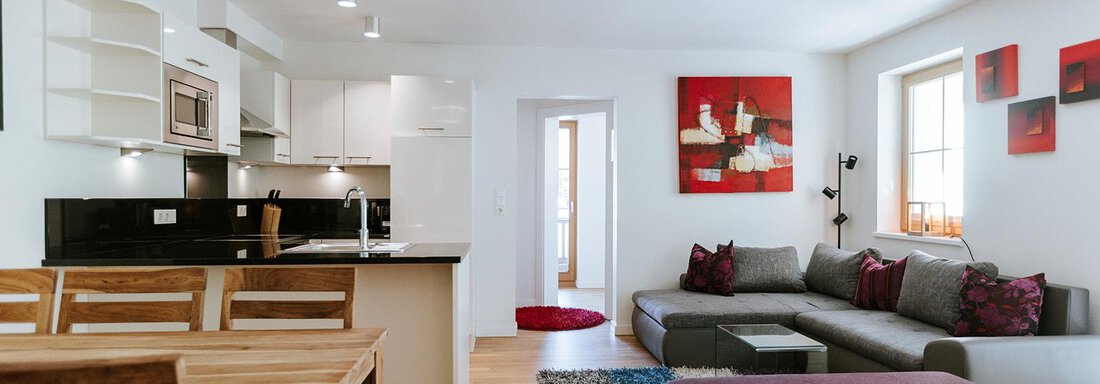 A modern living room with a comfortable couch and a wooden dining table. The walls are decorated with colorful pictures, and the room is bright and inviting. - Appartement Bergbach Sölden - Sölden